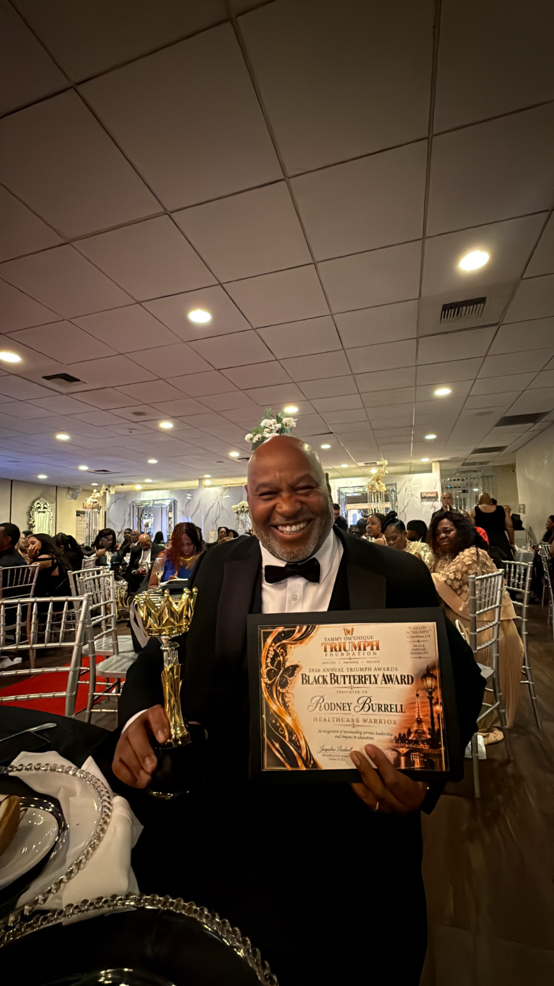 Rodney Burnell smiling while holding the 2026 Black Butterfly Award for Healthcare Warrior